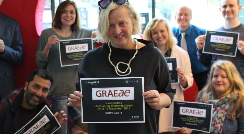 Image of some of Graeae's employees holding up signs supporting captioning awareness week