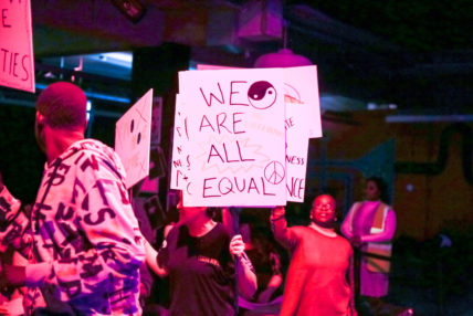 Participants holding up signs that read 'We are all equal'