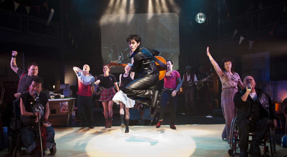 Image of man jumping in the air with serveral cast behind him on set of Reasons to be Cheerful