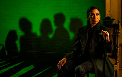 Image of woman sitting in black on green background