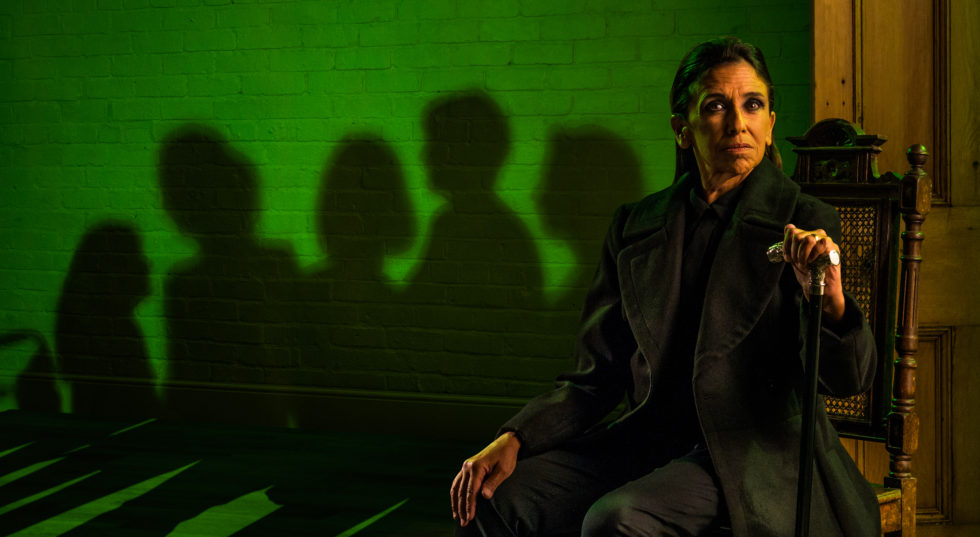 Image of woman sitting in black on green background