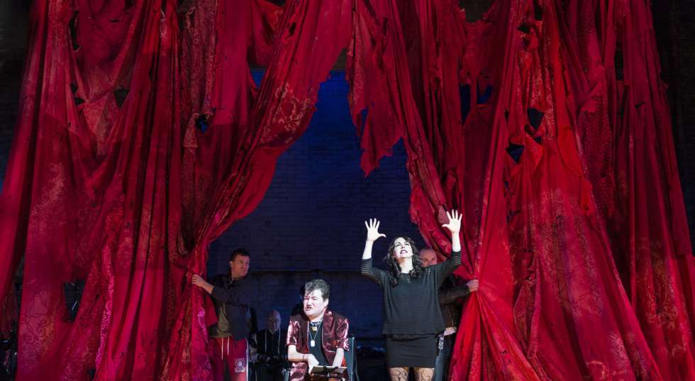 4 cast members on stage with long red curtains behind them