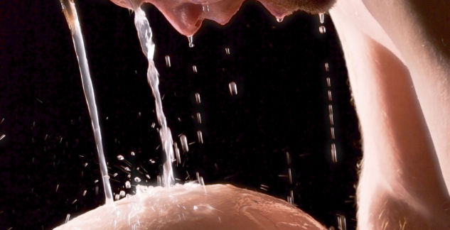 Image of a man, his head over the pregnant belly of a woman, whilst water pours from above.