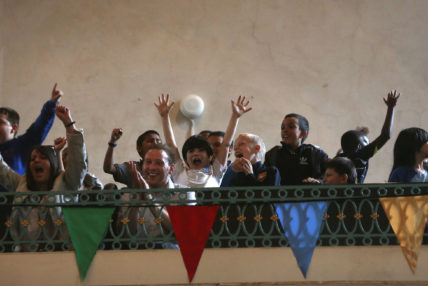 Image of Day of Games with cheering children on balcony.