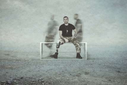 A man sits on a bench, whilst the blurry afterimages of other men flit behind him