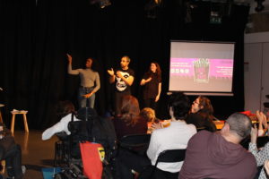 three actors standing at the front of the room with audiences heads