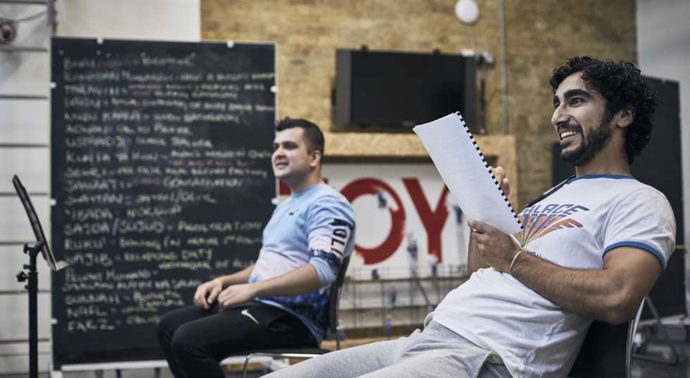Two cast members sitting in Graeae's rehearsal room looking at their script